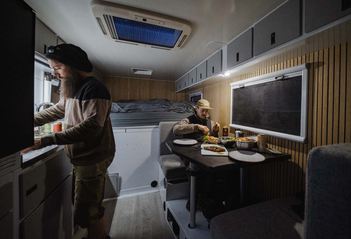 Inside the expedition truck: guest at the galley with dinner laid out on the dinette