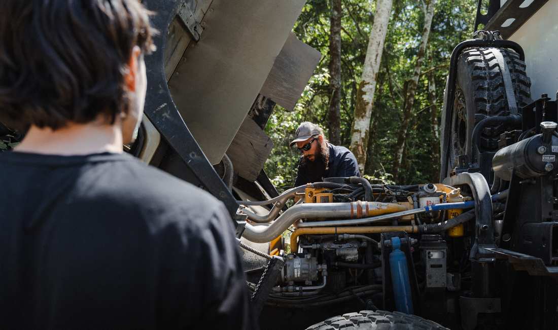 Technicians working under the raised body of an expedition truck