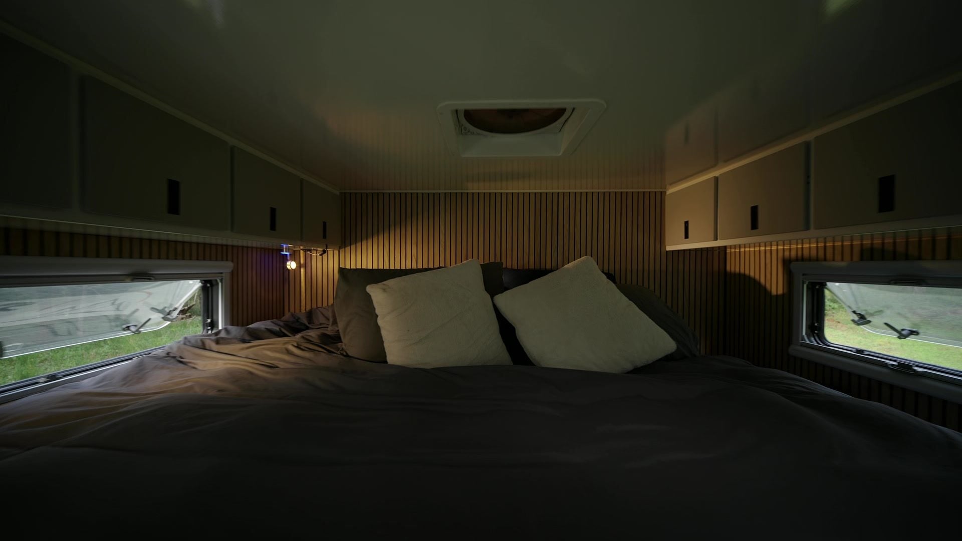 Roxanne's queen bed made up with pillows under the roof hatch in warm evening light